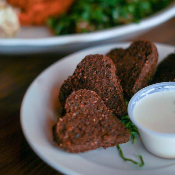 Heart-shaped falafel pieces with a side of white dipping sauce on a plate.