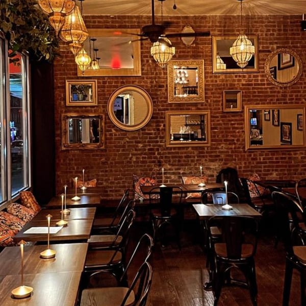 Cozy Dar525 dining room with brick walls, ornate mirrors, and warm Moroccan lanterns.