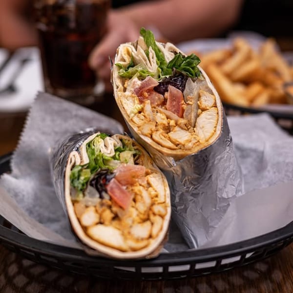 Two chicken shawarma wraps with lettuce, tomatoes, and onions, served with fries and a drink.
