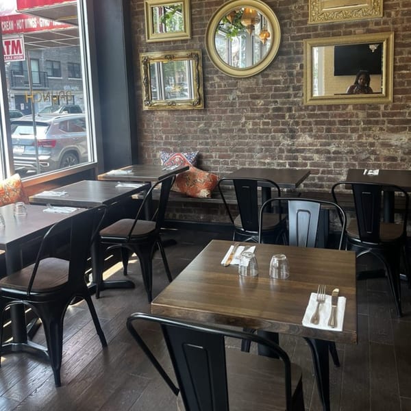 Dar525's dining area with wooden tables, black chairs, brick walls, and decorative mirrors.