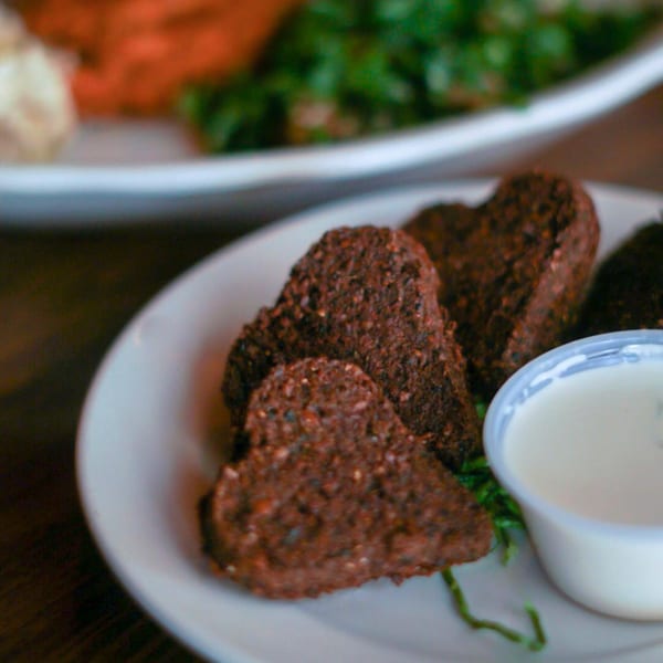 Heart-shaped falafel on a white plate with a side of white dipping sauce.