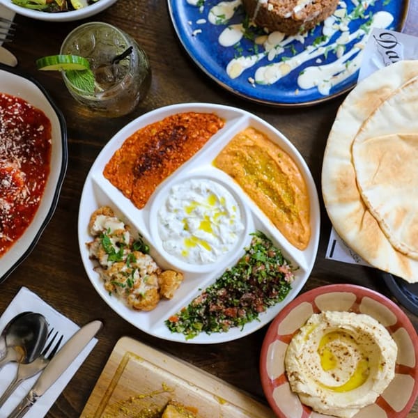Overhead view of a Dar525 Mediterranean mezze platter with dips, tabbouleh, cauliflower, and pita bread.