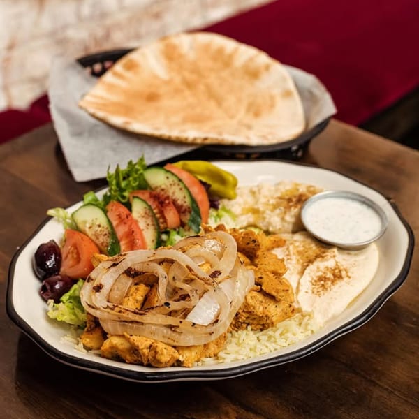 Dar525 Mediterranean chicken shawarma plate with rice, salad, hummus, and pita bread.