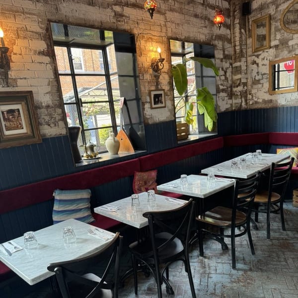Interior of Dar525, a Mediterranean restaurant, with marble tables, dark chairs, and brick walls.