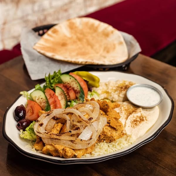 Mediterranean chicken shawarma plate with rice, salad, hummus, and pita bread.